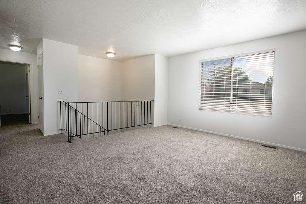 Carpeted spare room featuring a textured ceiling