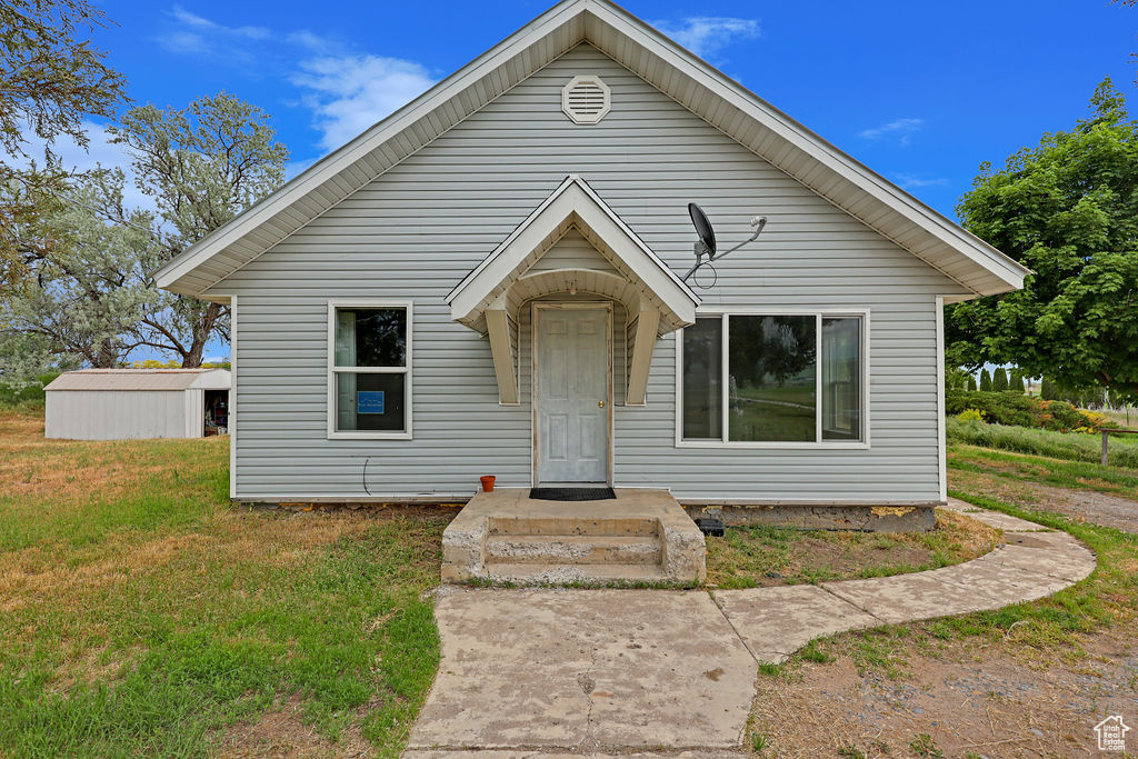 Bungalow-style home with an outdoor structure and a front lawn