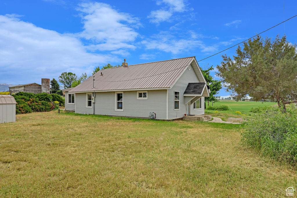 Rear view of house featuring an outdoor structure and a lawn