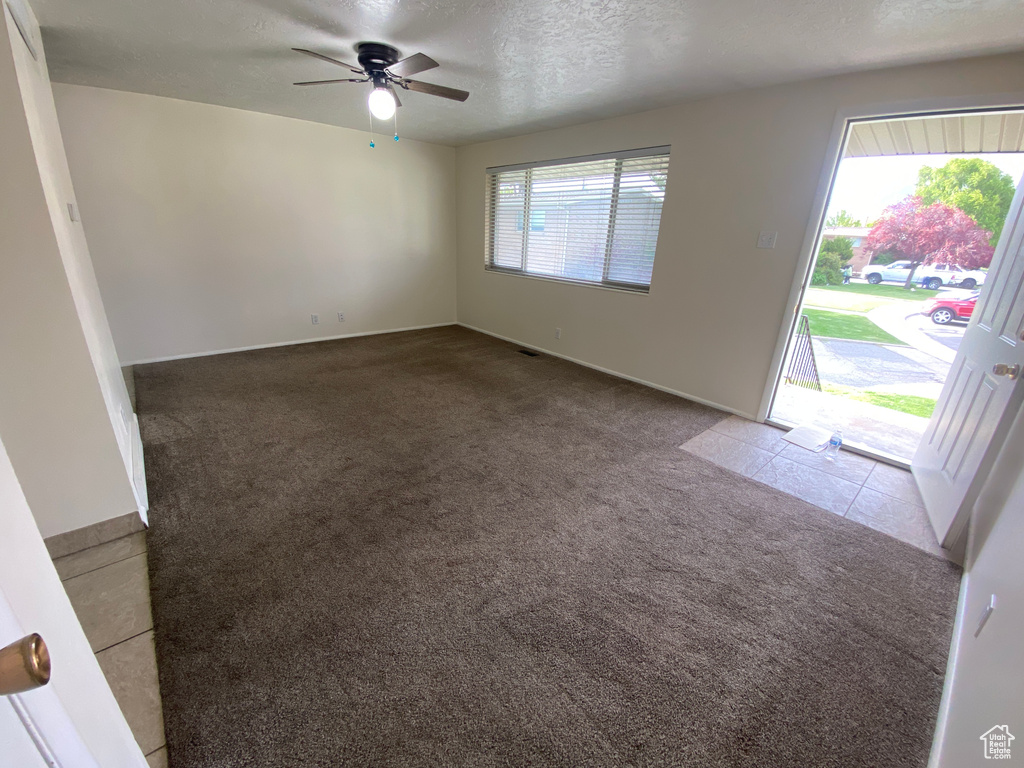 Empty room with a textured ceiling, carpet, and ceiling fan