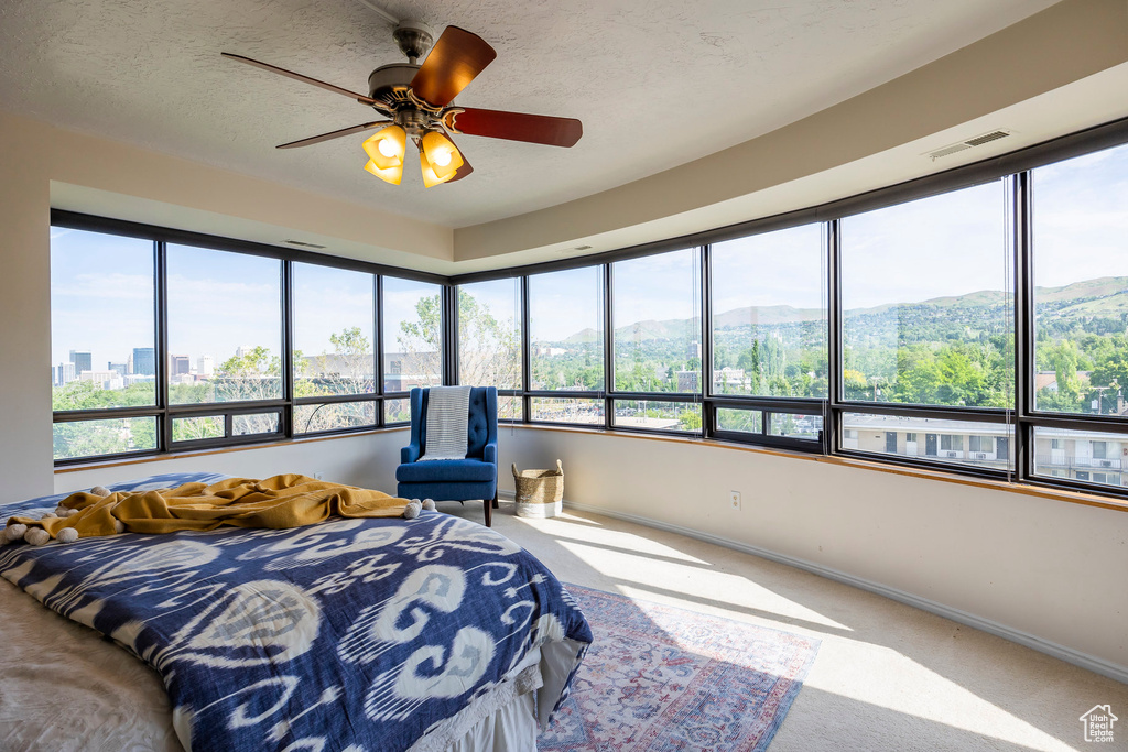 Bedroom featuring a mountain view, carpet, multiple windows, and ceiling fan