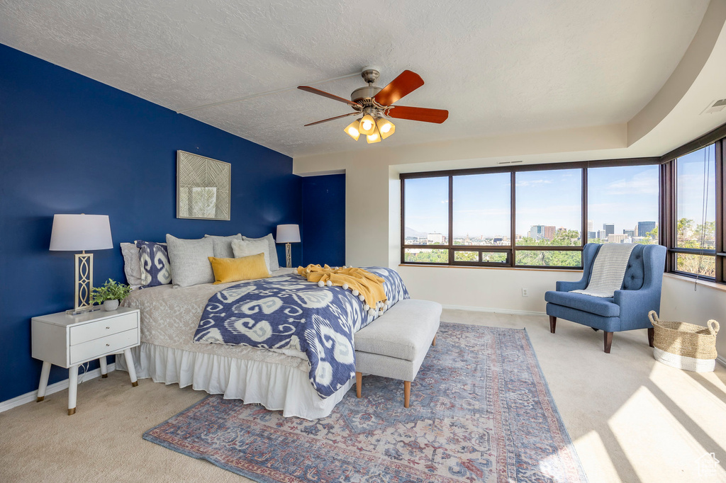 Bedroom featuring a textured ceiling, multiple windows, carpet, and ceiling fan