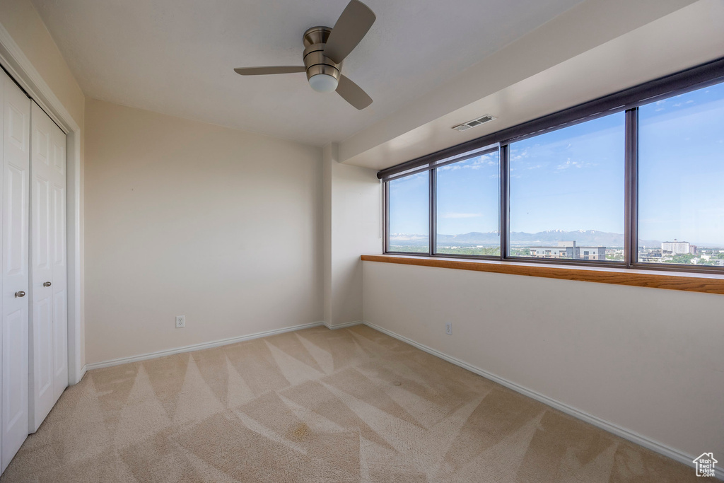 Unfurnished bedroom featuring ceiling fan, a closet, and light colored carpet