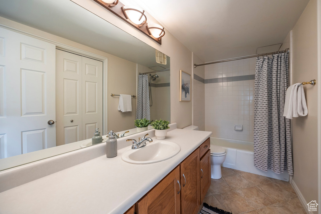 Full bathroom with shower / tub combo with curtain, vanity, tile patterned floors, and toilet