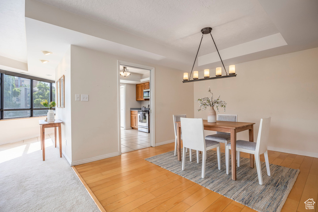 Dining room with a chandelier, light wood-type flooring, and a tray ceiling