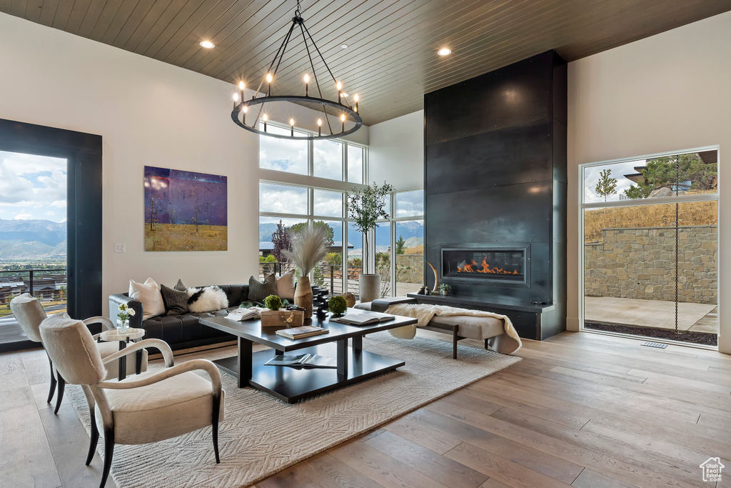 Living room featuring wooden ceiling, a high ceiling, light hardwood / wood-style flooring, and a fireplace