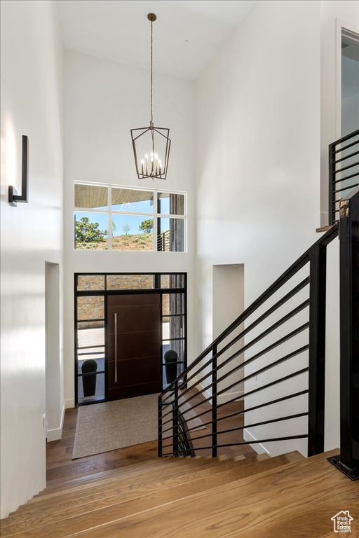 Foyer entrance with a high ceiling, hardwood / wood-style flooring, and a chandelier