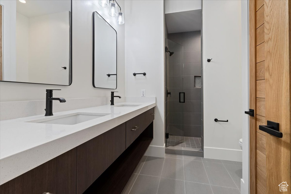 Bathroom featuring double vanity, walk in shower, toilet, and tile floors