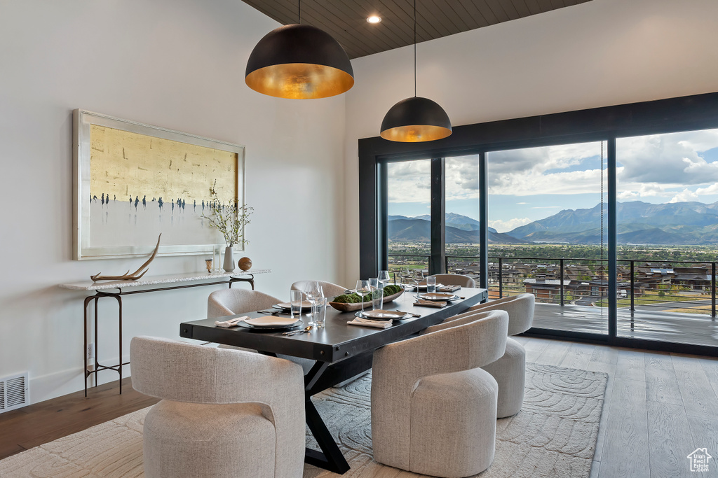 Dining area with a high ceiling, a mountain view, and light hardwood / wood-style floors