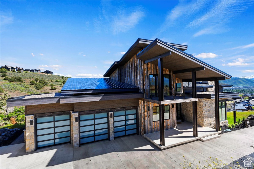 Contemporary house featuring a garage, a balcony, and a mountain view