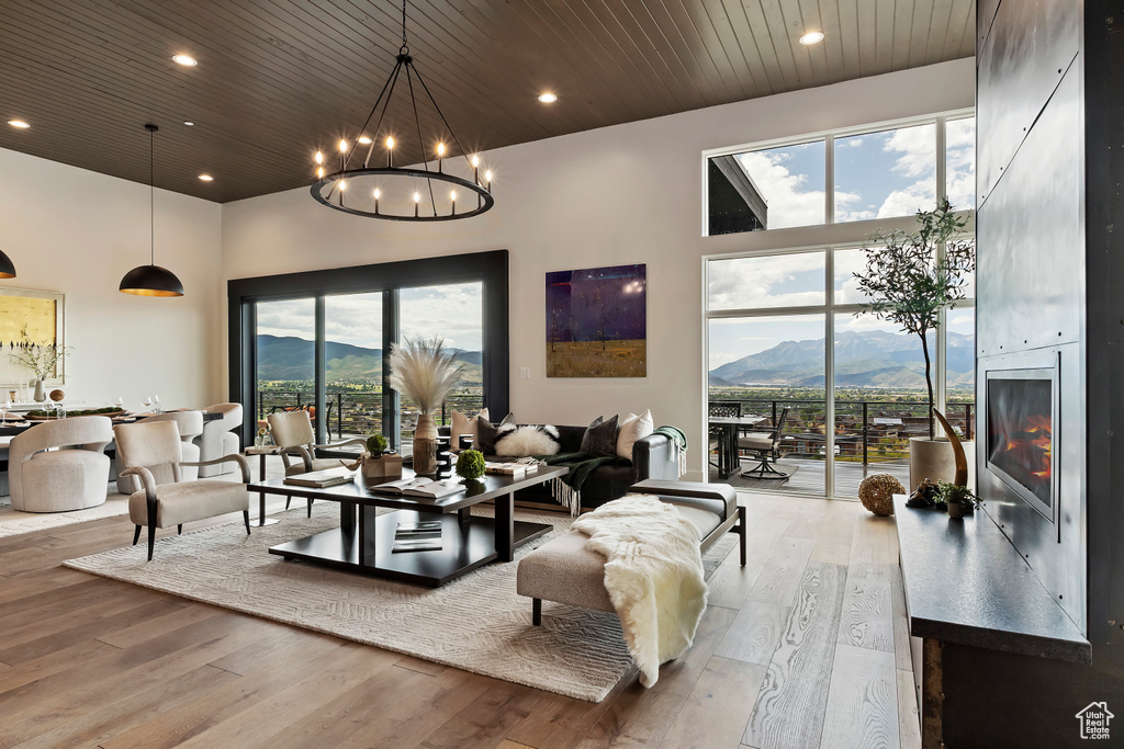 Living room with light wood-type flooring, a mountain view, a towering ceiling, and plenty of natural light