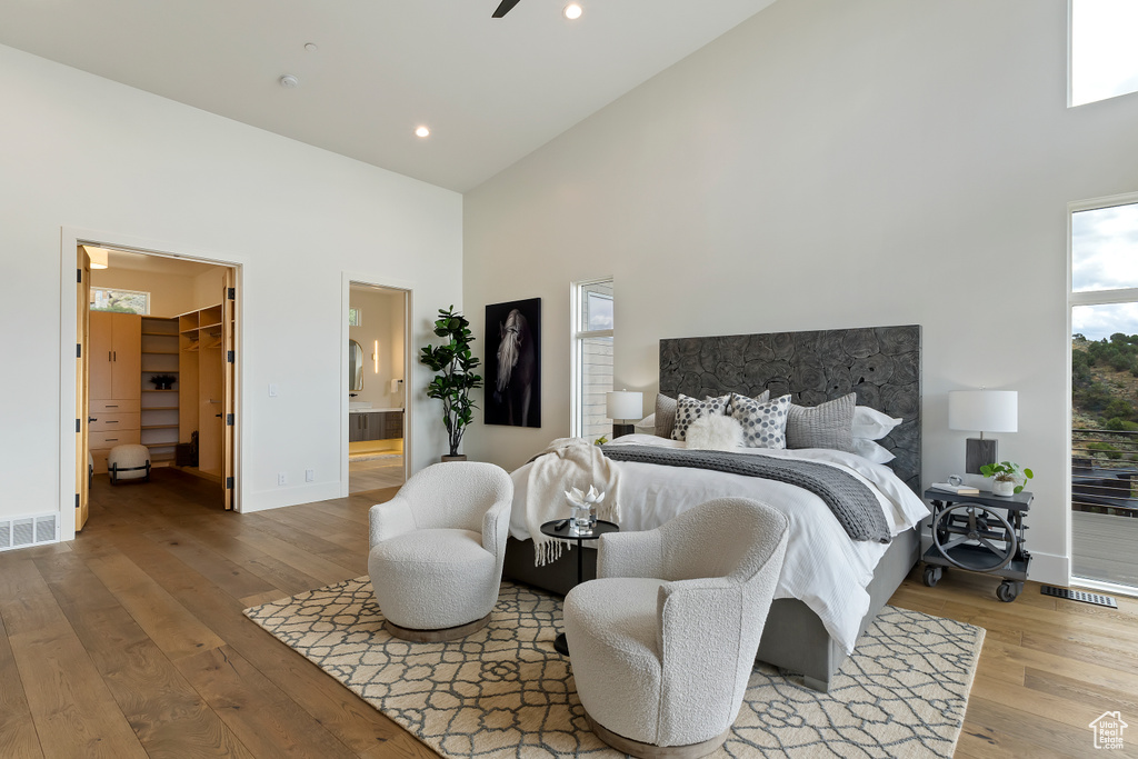 Bedroom featuring a high ceiling, ensuite bath, wood-type flooring, a closet, and a spacious closet