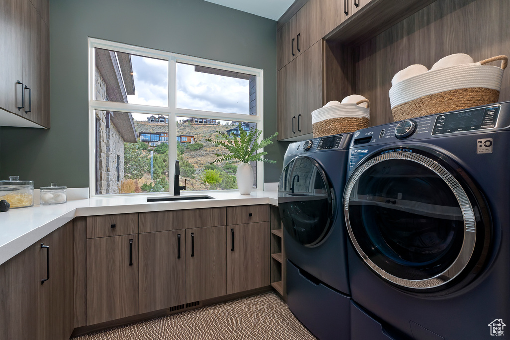 Washroom with sink, washer and clothes dryer, and cabinets