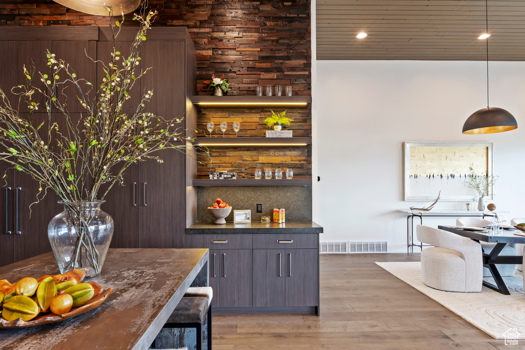 Bar with light hardwood / wood-style flooring, pendant lighting, and decorative backsplash