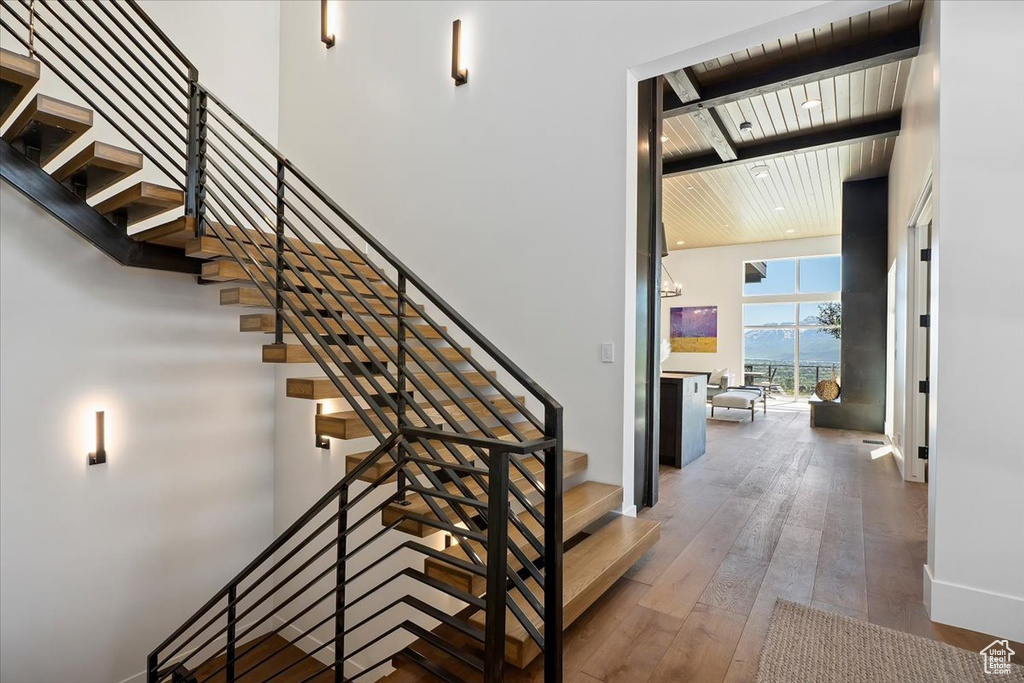 Stairway featuring beam ceiling, wooden ceiling, hardwood / wood-style flooring, and a towering ceiling