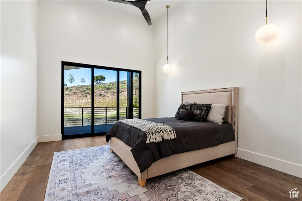 Bedroom featuring a towering ceiling, hardwood / wood-style flooring, and access to exterior