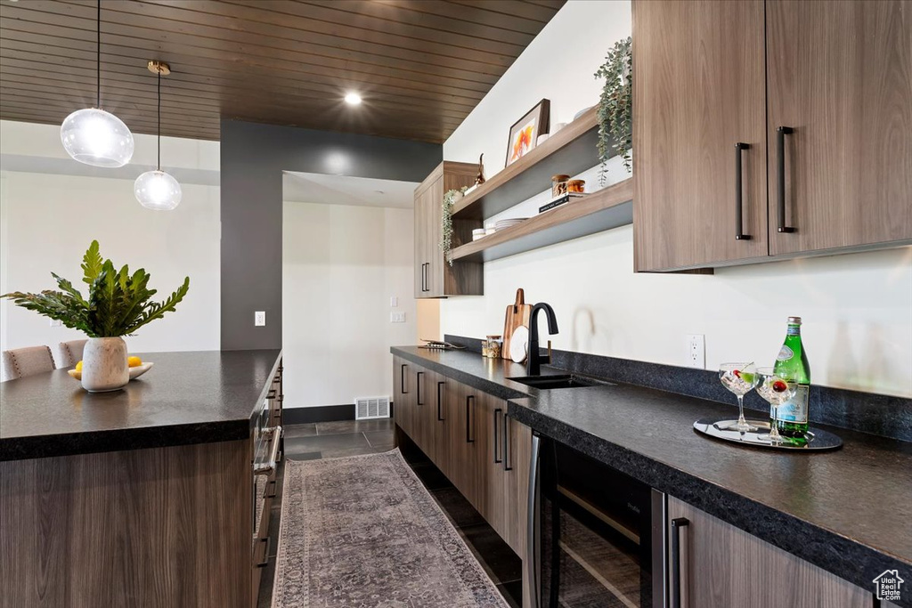 Kitchen featuring sink, decorative light fixtures, dark tile patterned flooring, and beverage cooler