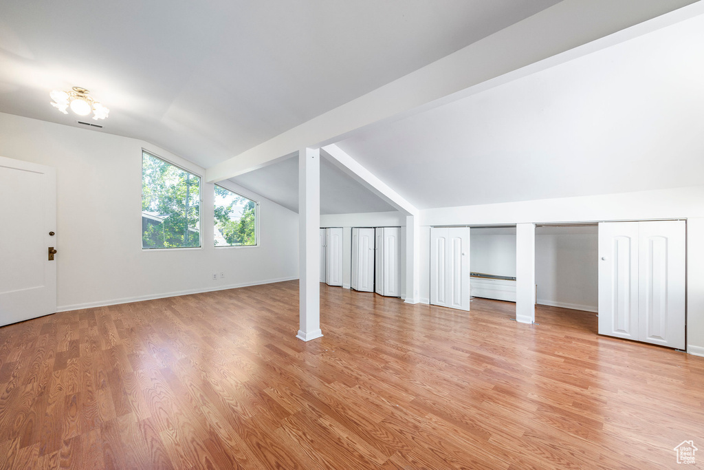 Bonus room with lofted ceiling with beams and light hardwood / wood-style flooring