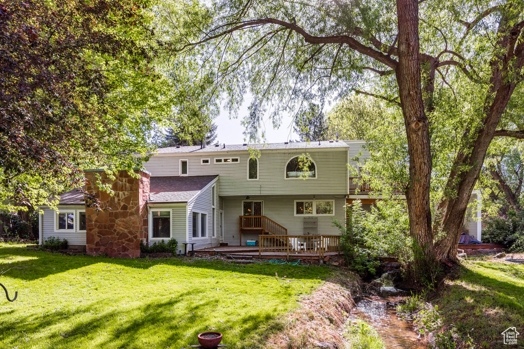 Back of property featuring a deck and a lawn