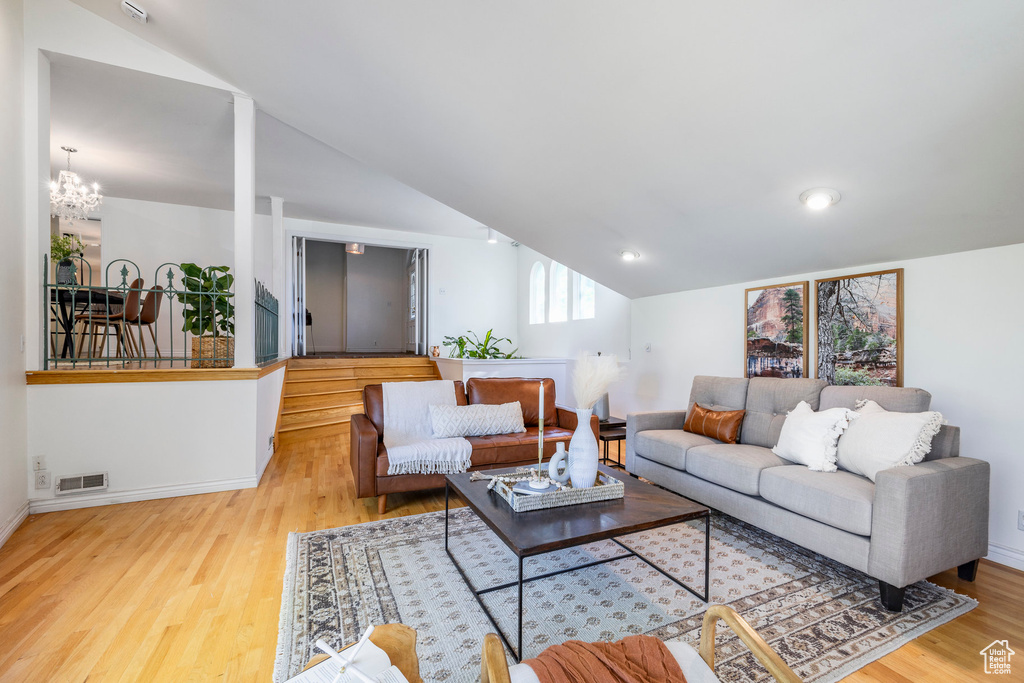 Living room featuring light hardwood / wood-style floors, a chandelier, and vaulted ceiling