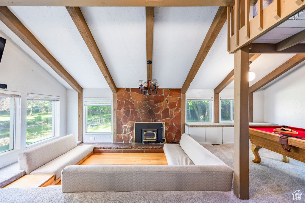 Living room featuring a wealth of natural light, carpet, a stone fireplace, and billiards