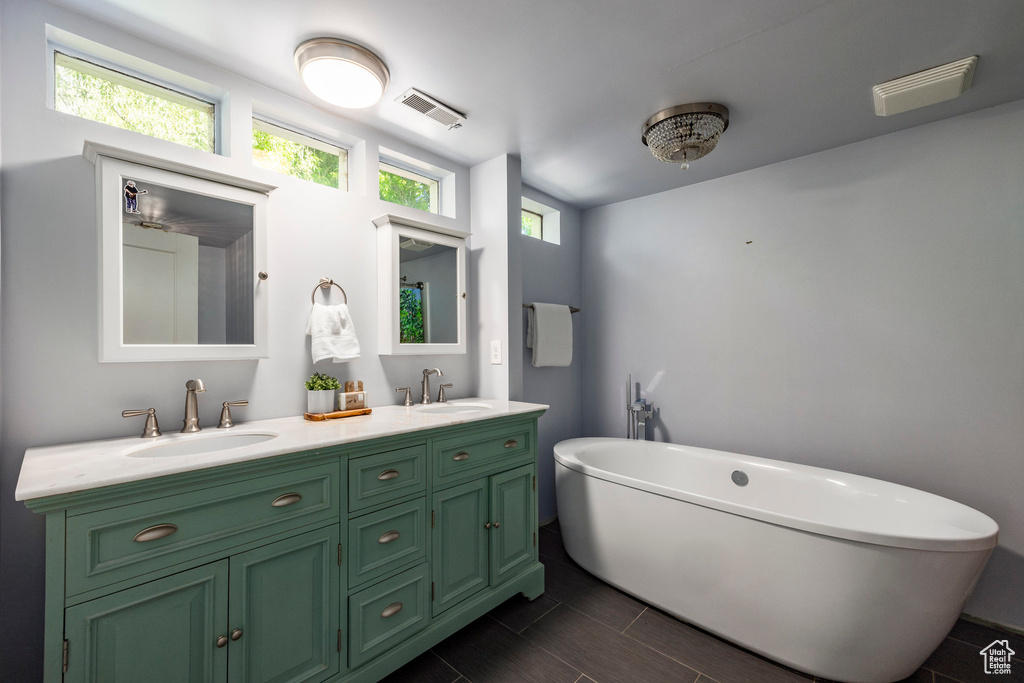 Bathroom with dual bowl vanity, tile flooring, and a bathtub