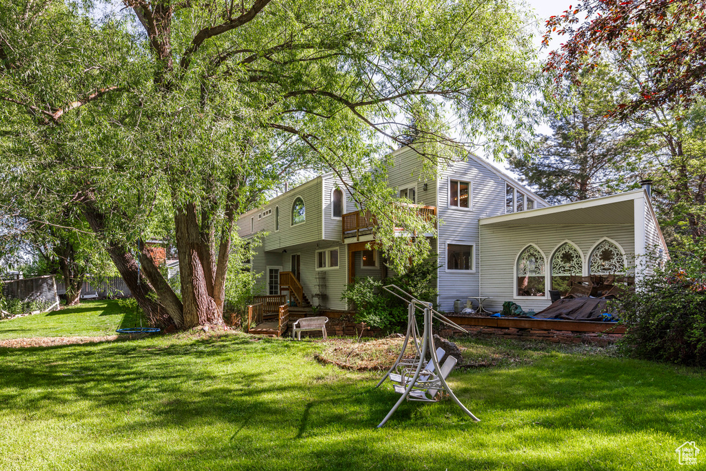 Back of house featuring a lawn and a wooden deck