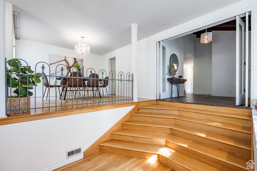 Staircase featuring wood-type flooring and a chandelier