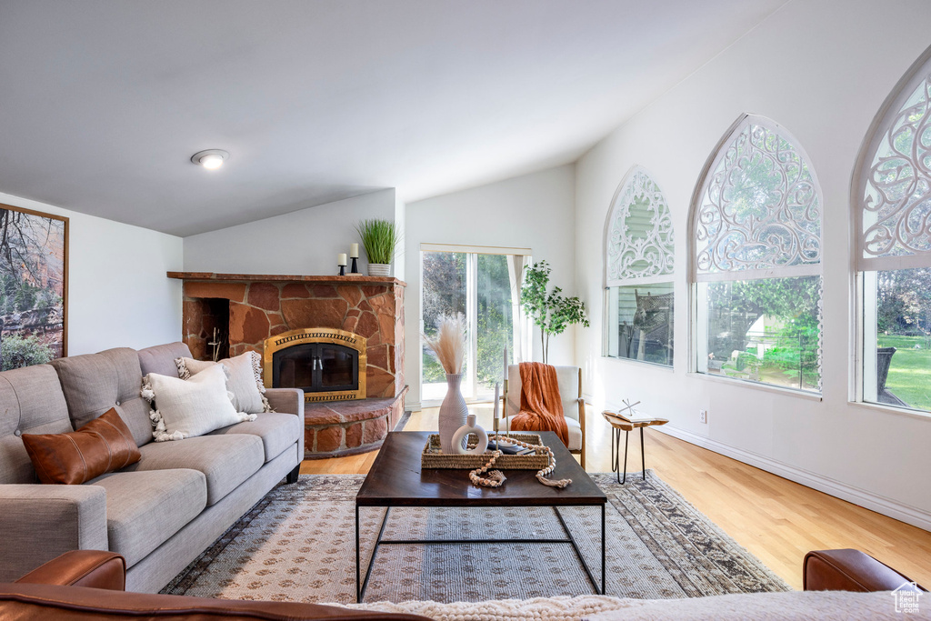 Living room with wood-type flooring, a fireplace, and lofted ceiling