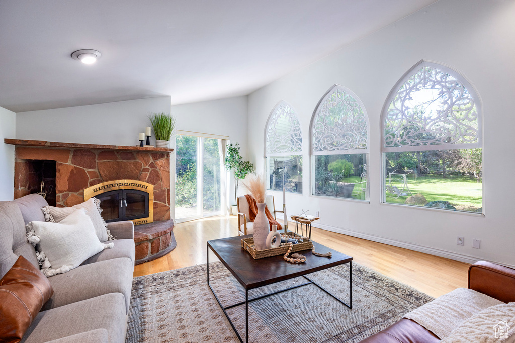 Living room with a stone fireplace, lofted ceiling, and hardwood / wood-style floors