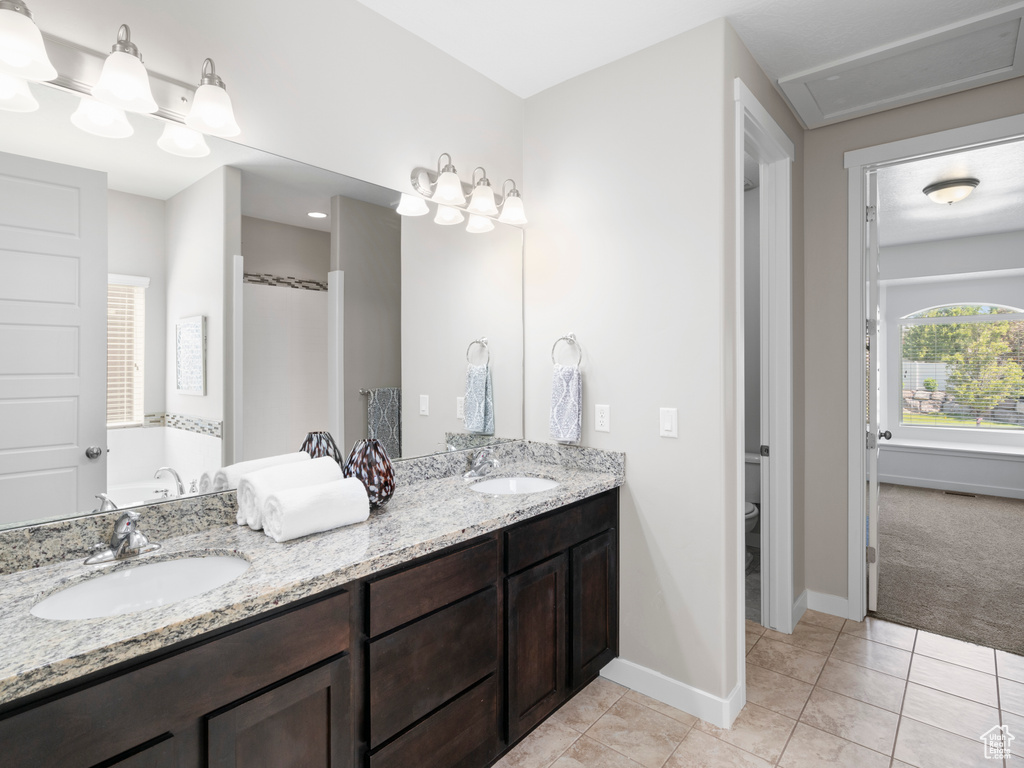 Bathroom with tile flooring, toilet, and double sink vanity