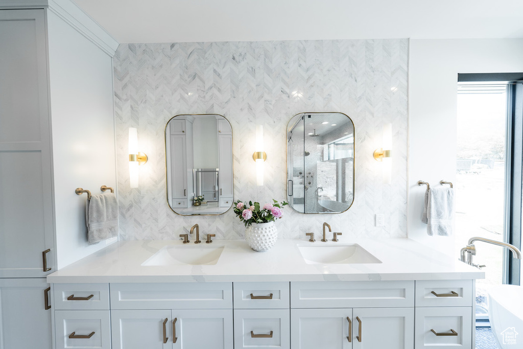 Bathroom with dual bowl vanity, a washtub, and tasteful backsplash