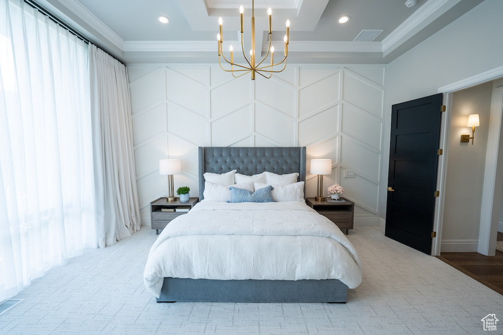 Bedroom featuring hardwood / wood-style floors, ornamental molding, a chandelier, and a raised ceiling