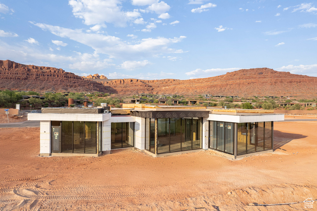 Rear view of property with a mountain view and a sunroom