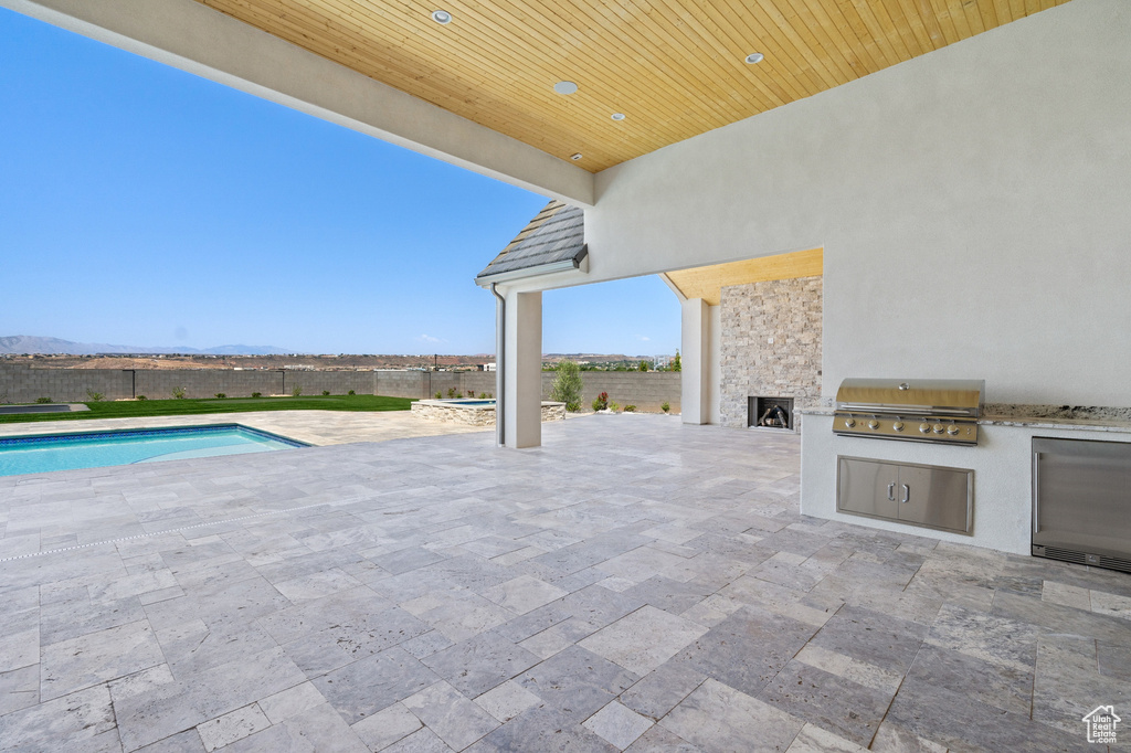 View of patio with a grill, an outdoor kitchen, and a fenced in pool