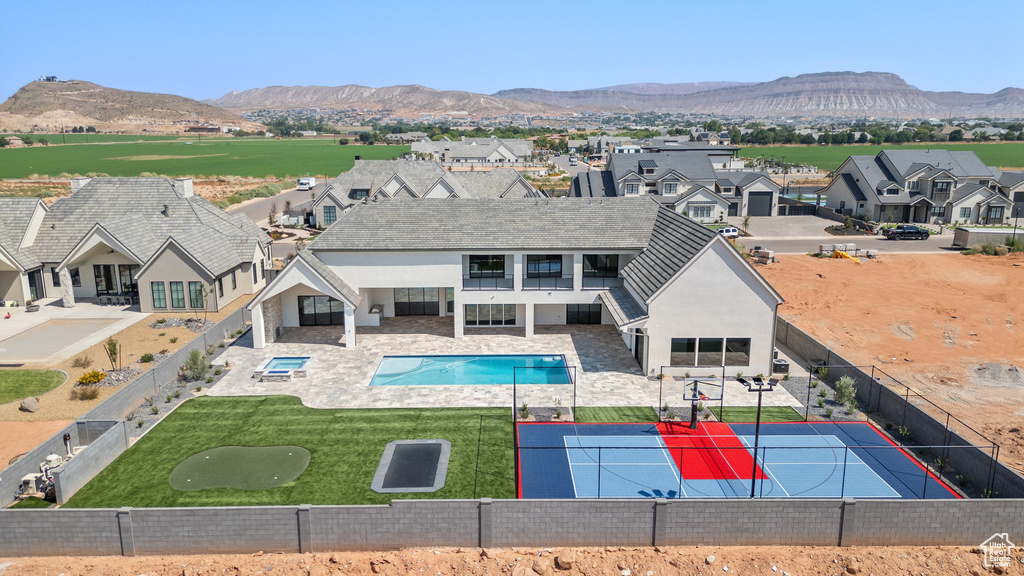 Rear view of property with a fenced in pool, a lawn, a mountain view, and a patio