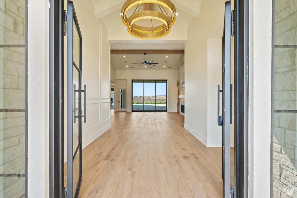 Foyer featuring ceiling fan with notable chandelier, light wood-type flooring, and lofted ceiling with beams