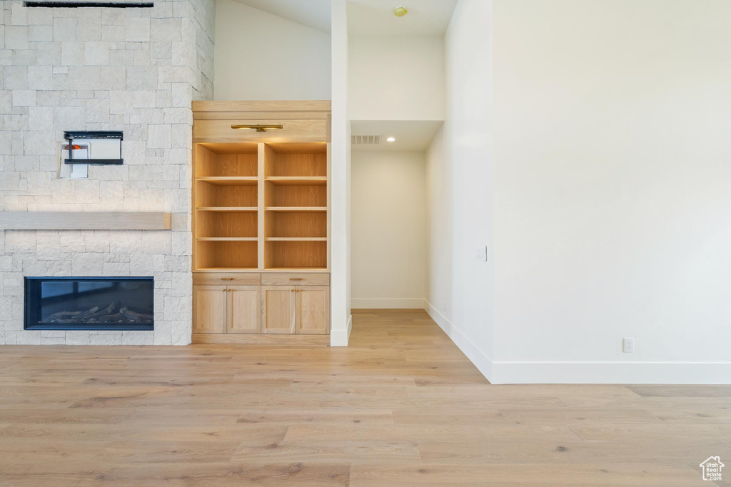 Unfurnished living room with a stone fireplace, vaulted ceiling, and hardwood / wood-style floors