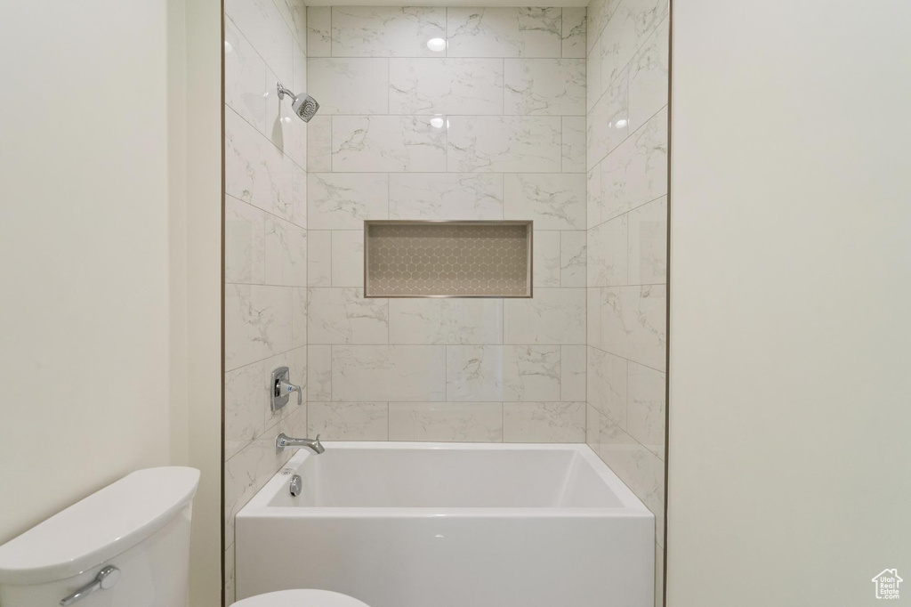 Bathroom featuring tiled shower / bath and toilet