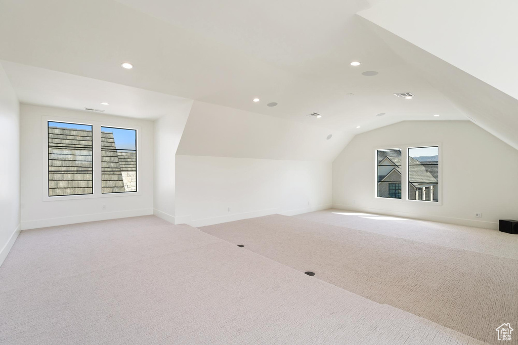 Additional living space featuring light carpet and vaulted ceiling