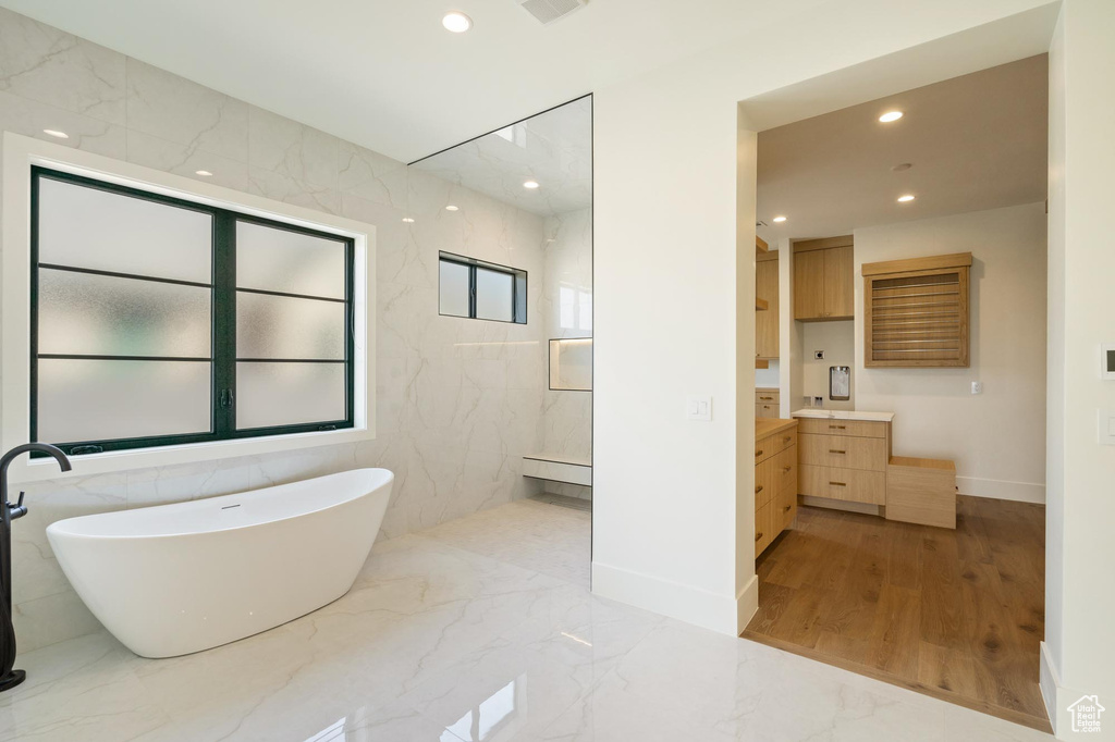 Bathroom with vanity, wood-type flooring, tile walls, and a washtub