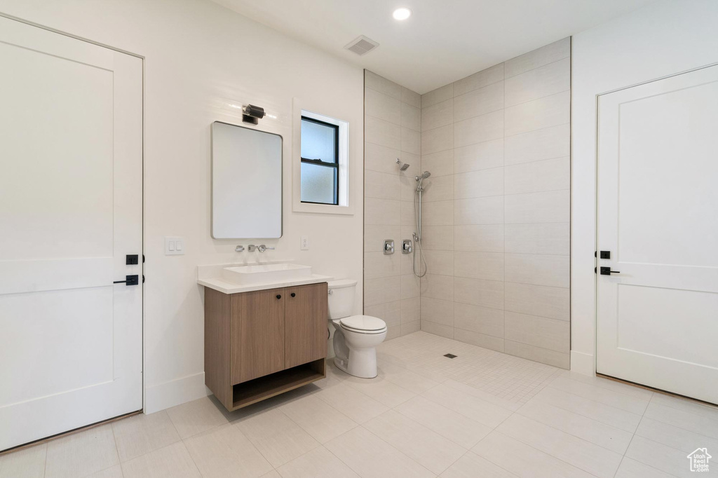 Bathroom with tile patterned floors, toilet, a tile shower, and vanity