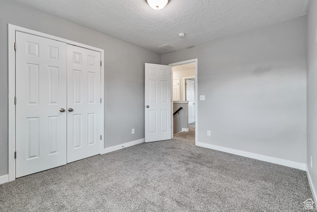 Unfurnished bedroom featuring carpet, a closet, and a textured ceiling