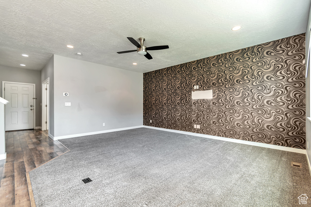 Spare room with ceiling fan, dark colored carpet, and a textured ceiling