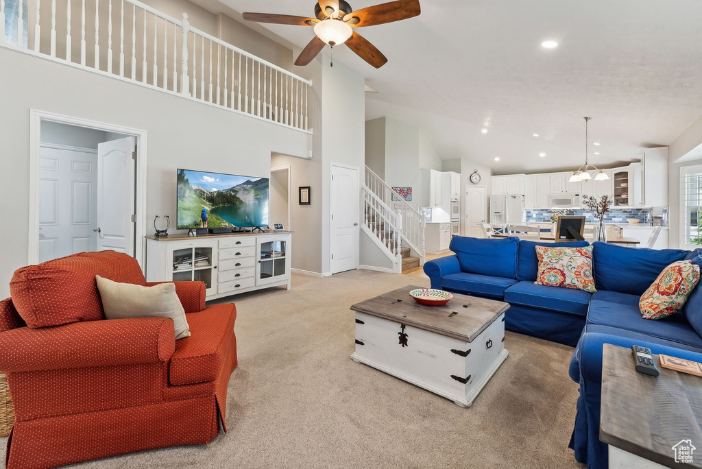 Carpeted living room with ceiling fan and a towering ceiling