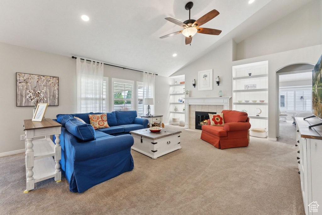 Carpeted living room featuring high vaulted ceiling, built in features, ceiling fan, and a fireplace