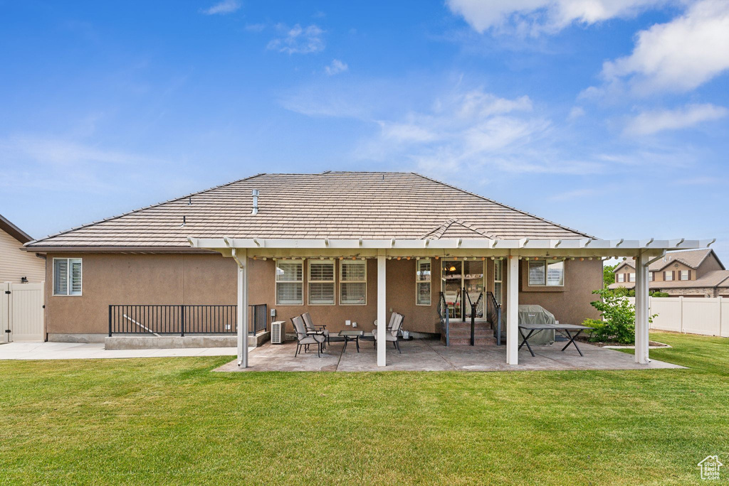 Rear view of house featuring a lawn, central AC unit, and a patio area