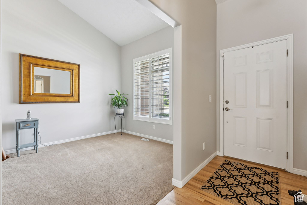 Carpeted entryway featuring lofted ceiling