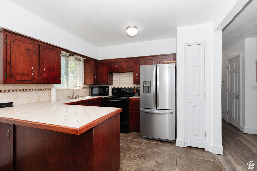 Kitchen with sink, kitchen peninsula, backsplash, and black appliances