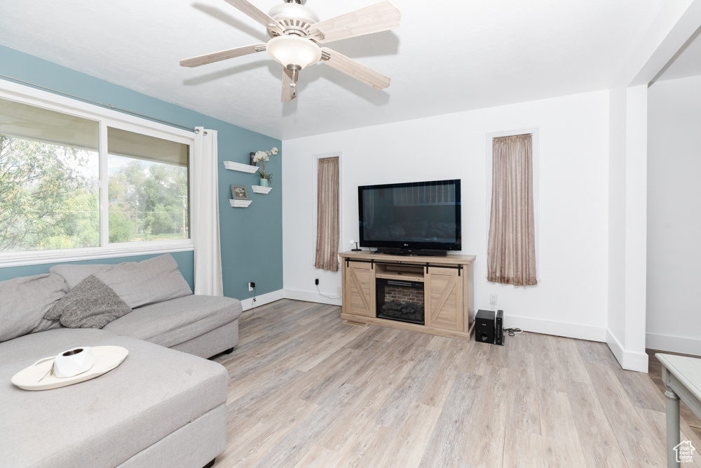 Living room with ceiling fan and light hardwood / wood-style floors